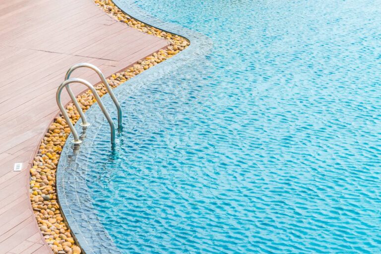Swimming pool with stainless steel ladder, wooden deck and clear blue water